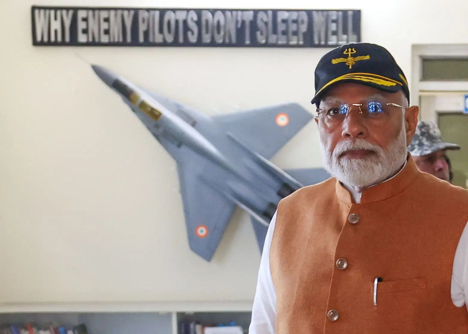 Message for Pakistan: Modi poses in front of a fighter jet image with a caption that says...